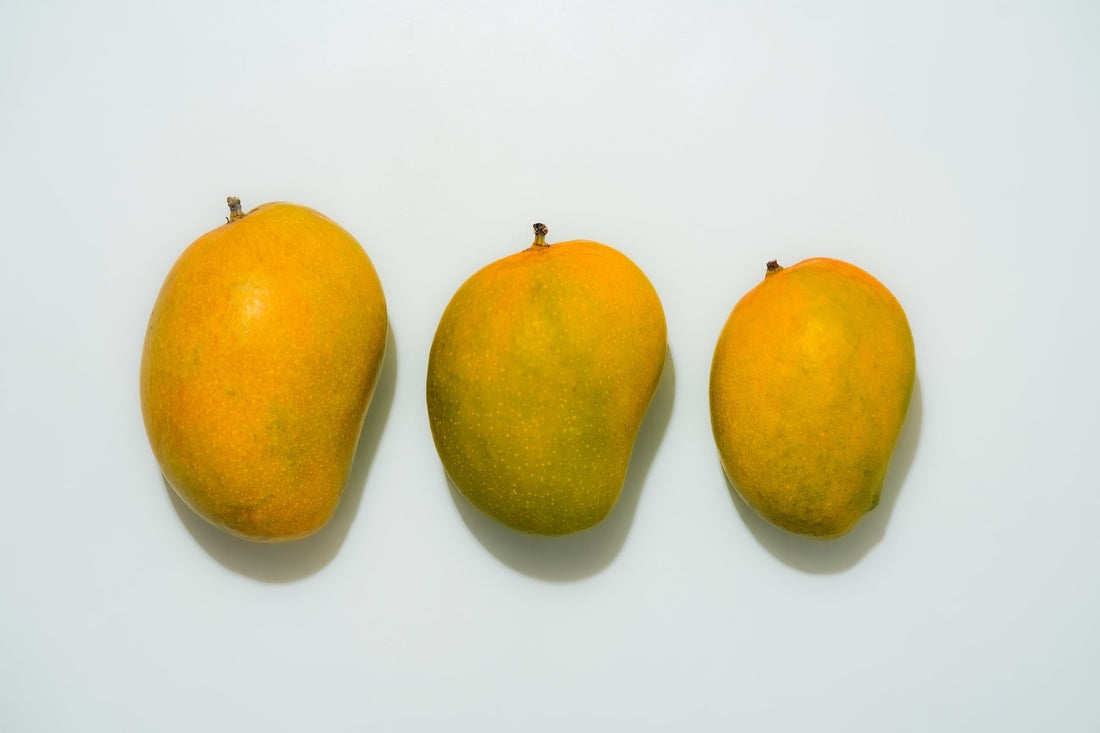 3 different sizes of mango placed on a plane white surface.