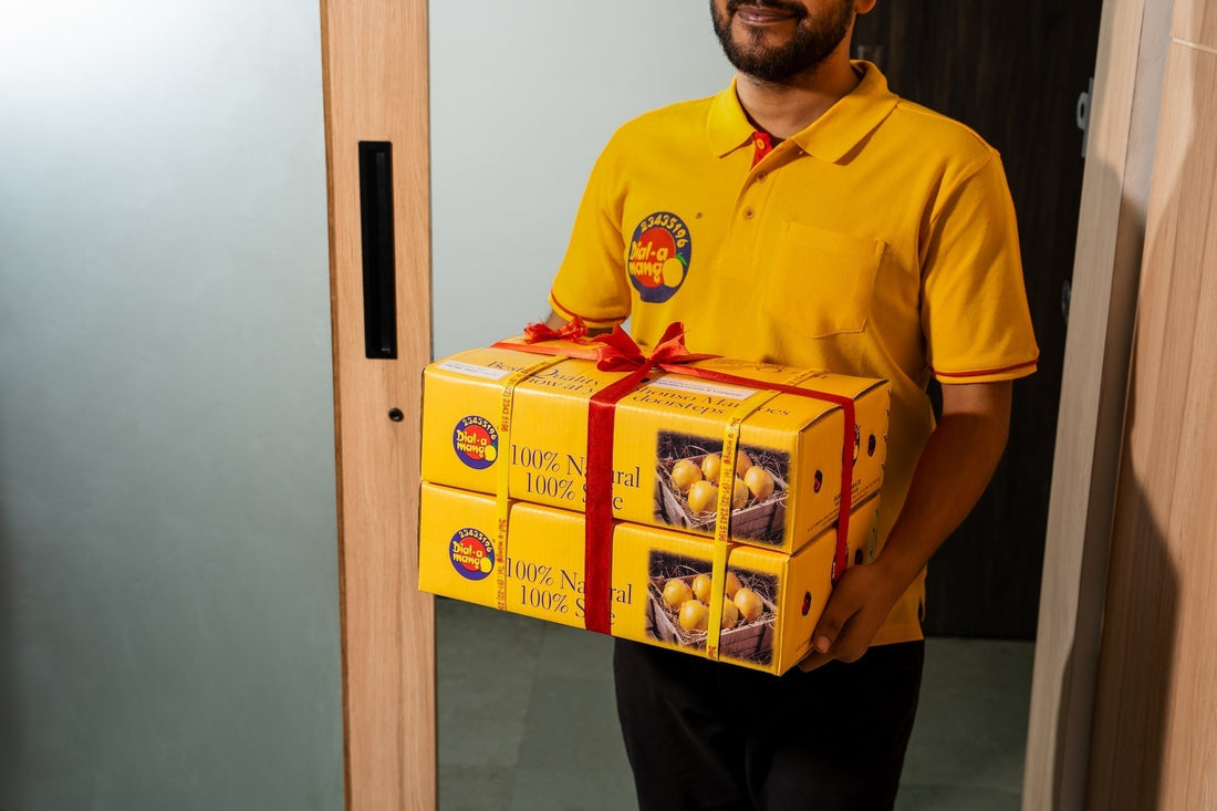 Delivery staff standing at the doorstep to deliver packaged boxes of fresh alphonso mangoes.